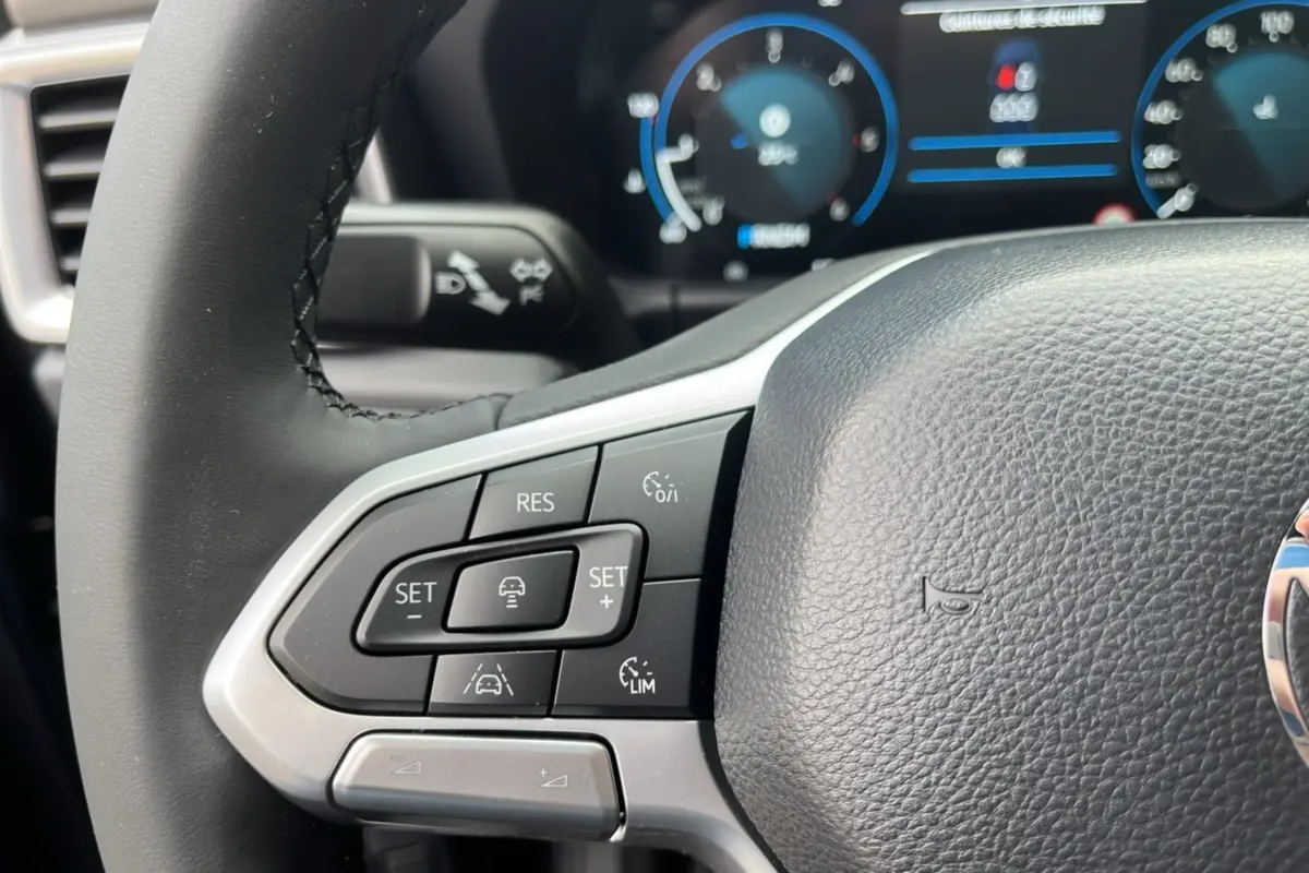Gros plan sur le volant noir du Volkswagen Amarok Simple Cabine 2025, avec commandes de régulateur de vitesse visibles.