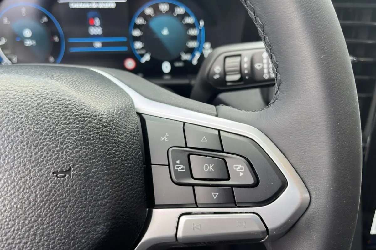 Gros plan sur les commandes multifonctions à droite du volant en cuir noir du Volkswagen Amarok Simple Cabine 2025.