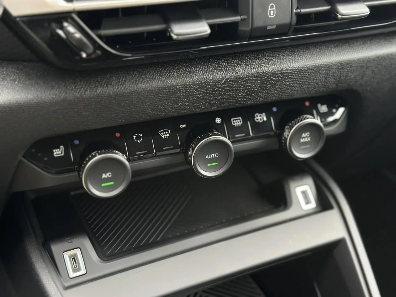 Gros plan sur la console centrale noire du Citroën C4 Manhattan Green 2025, avec commandes climatisation et USB visible.