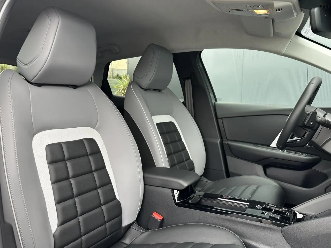 Vue intérieure côté conducteur de la Citroën C4 2025, sièges Advanced Comfort gris et noir avec accoudoir central.