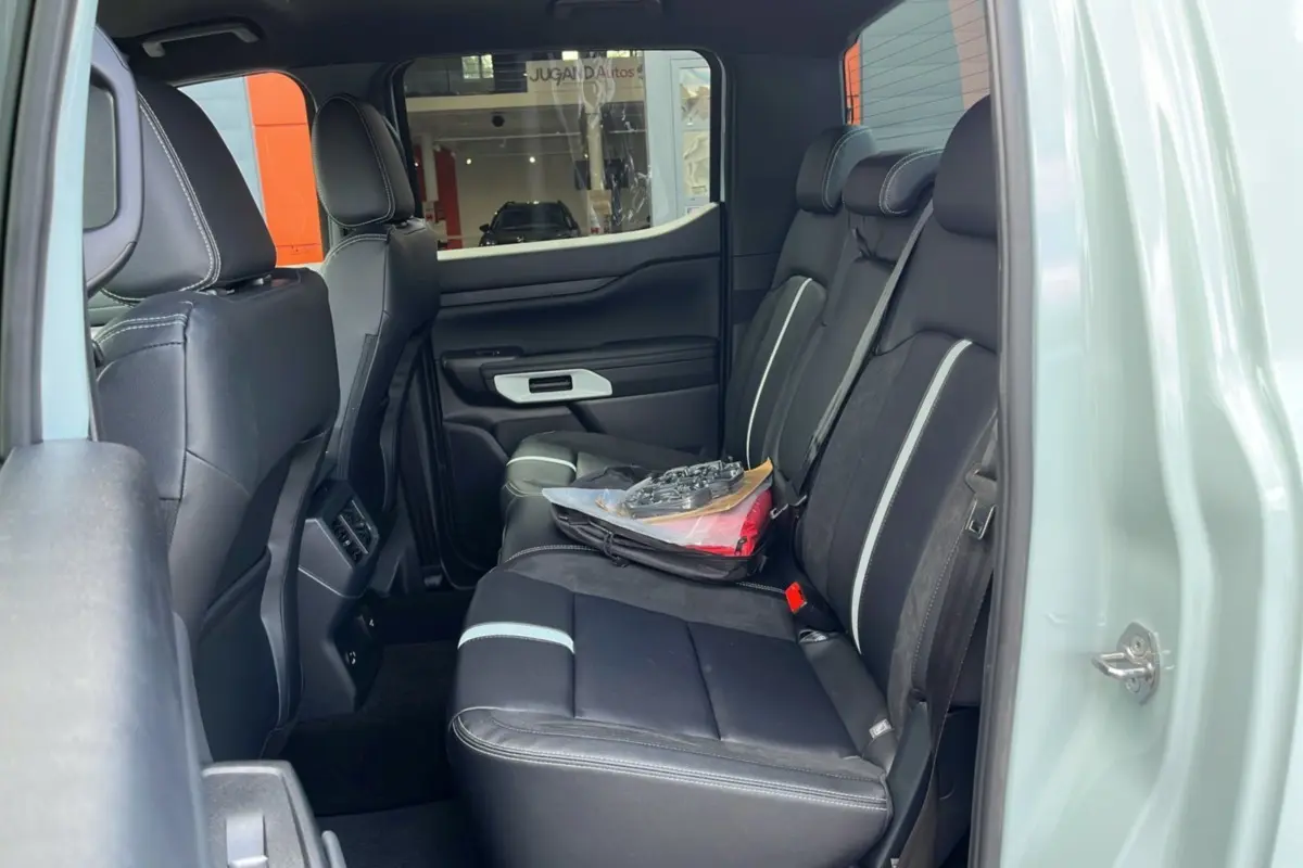 Vue latérale intérieure arrière du Ford Ranger 2.3 PHEV gris zen, sièges noirs avec surpiqûres blanches et vitres surteintées.