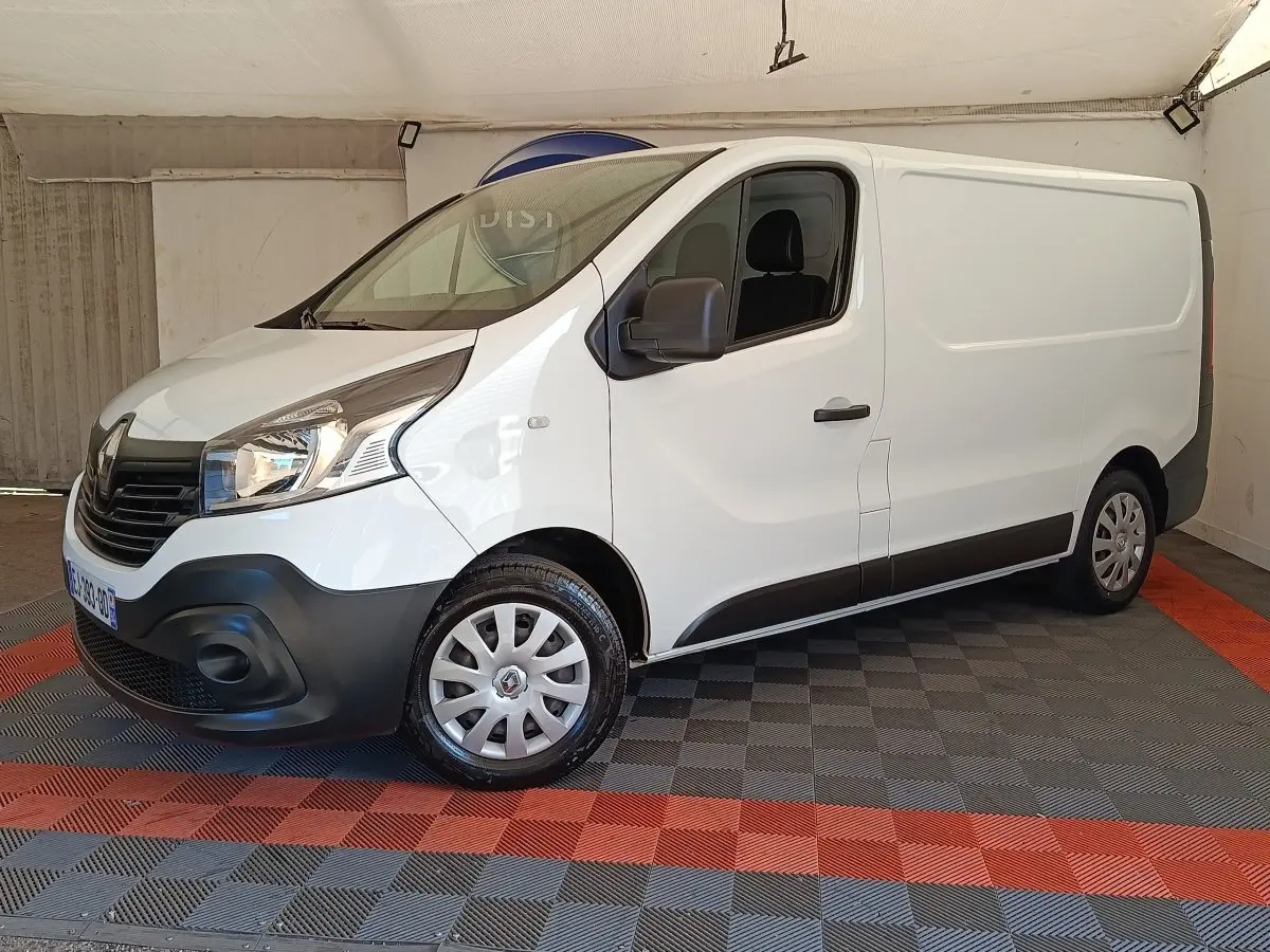 Fourgon Renault Trafic blanc vu en 3/4 avant droit, avec pare-chocs noir et jantes acier à enjoliveurs.