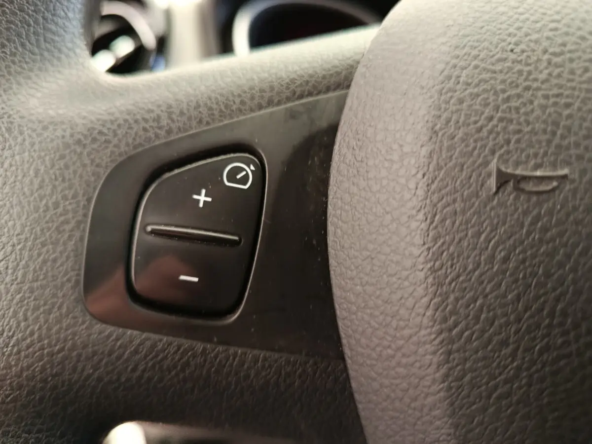 Gros plan sur le volant du Renault Trafic Fourgon 2017, bouton de réglage de l'éclairage visible sur cuir noir.