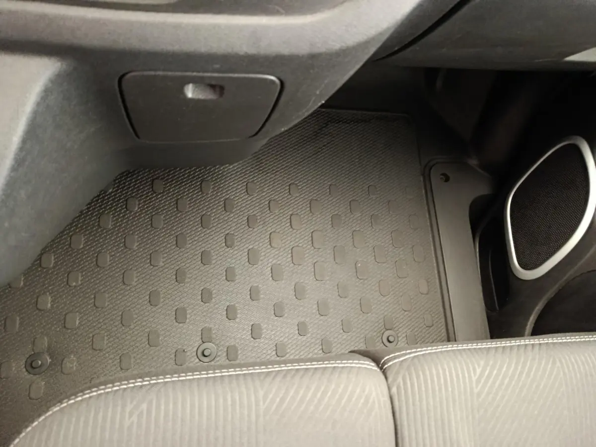 Vue intérieure du plancher côté passager avant avec tapis caoutchouc noir et partie inférieure de siège gris du Renault Trafic Fourgon blanc.