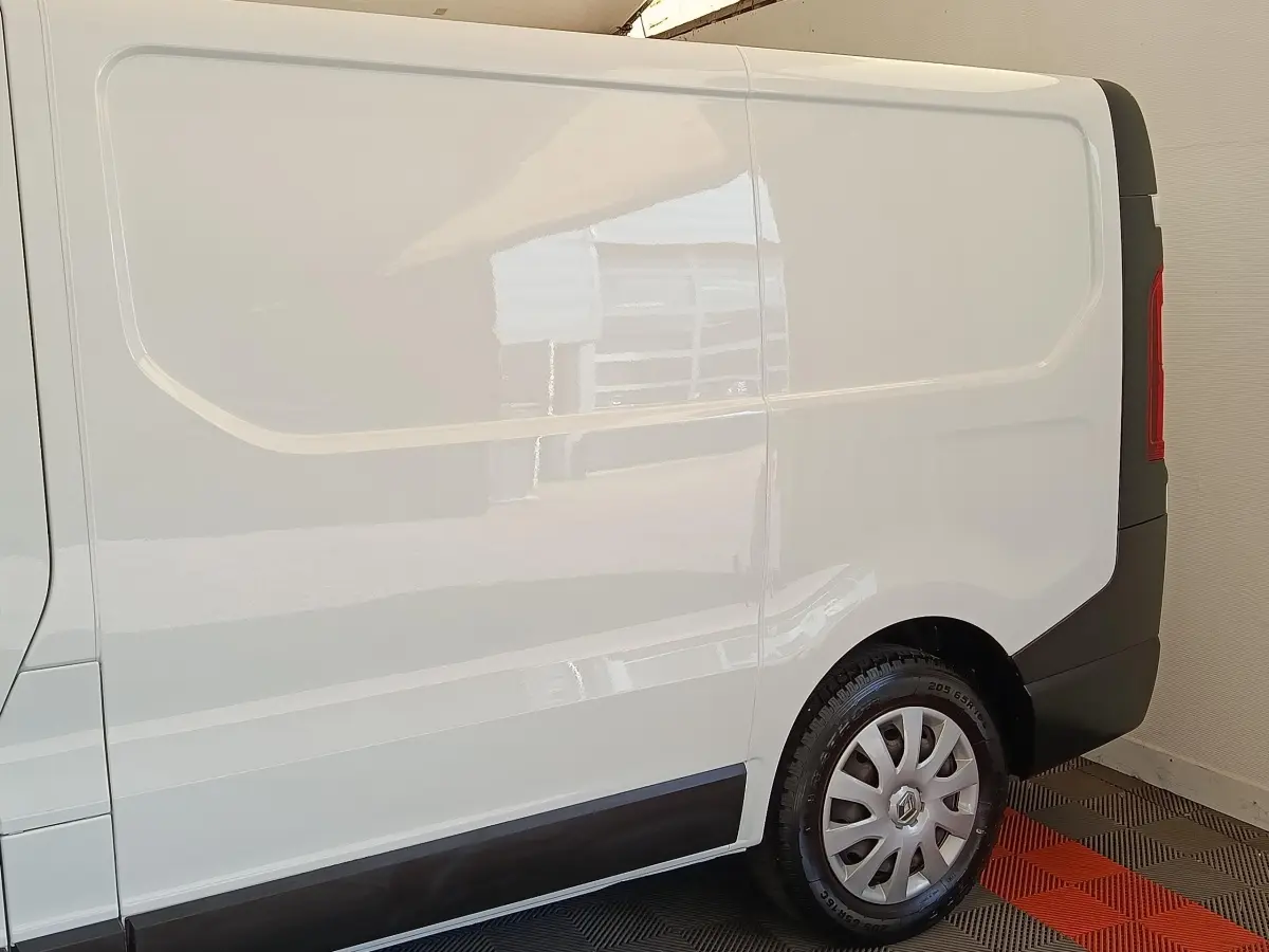 Profil droit du fourgon utilitaire Renault Trafic blanc, avec jante acier et enjoliveur gris.