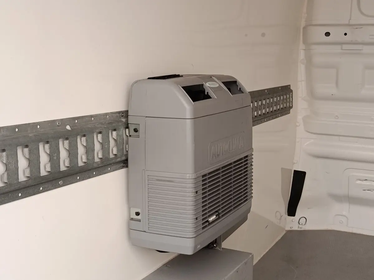 Détail intérieur montrant le système de climatisation Autoclima fixé sur la paroi blanche du Renault Trafic Fourgon blanc.