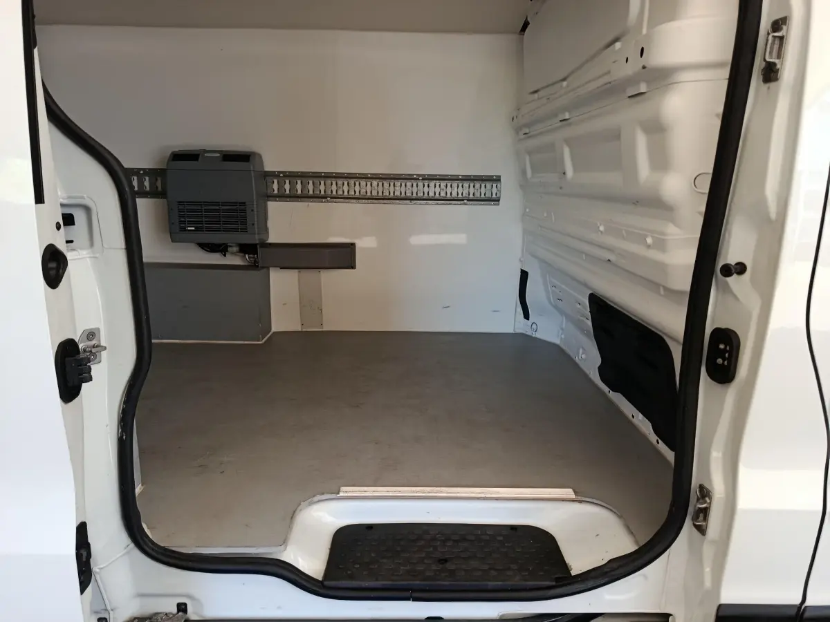 Vue intérieure arrière du fourgon blanc Renault Trafic, montrant l’espace de chargement vide avec cloison pleine.