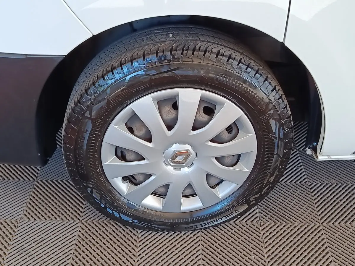 Gros plan sur la roue avant droite d’un Renault Trafic blanc, avec enjoliveur argenté et pneu Continental noir.