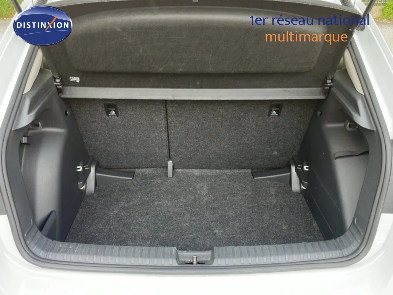 Coffre ouvert vu de l'arrière d'une Skoda Fabia blanc glacier, montrant l'espace de chargement vide et la moquette grise.