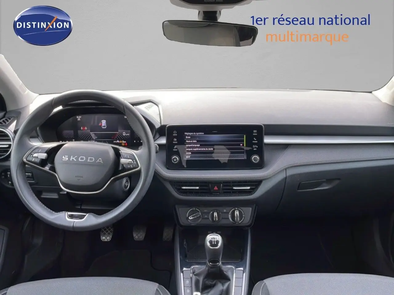 Vue intérieure avant du tableau de bord et volant SKODA Fabia 2025 avec écran tactile et levier de vitesses manuel.