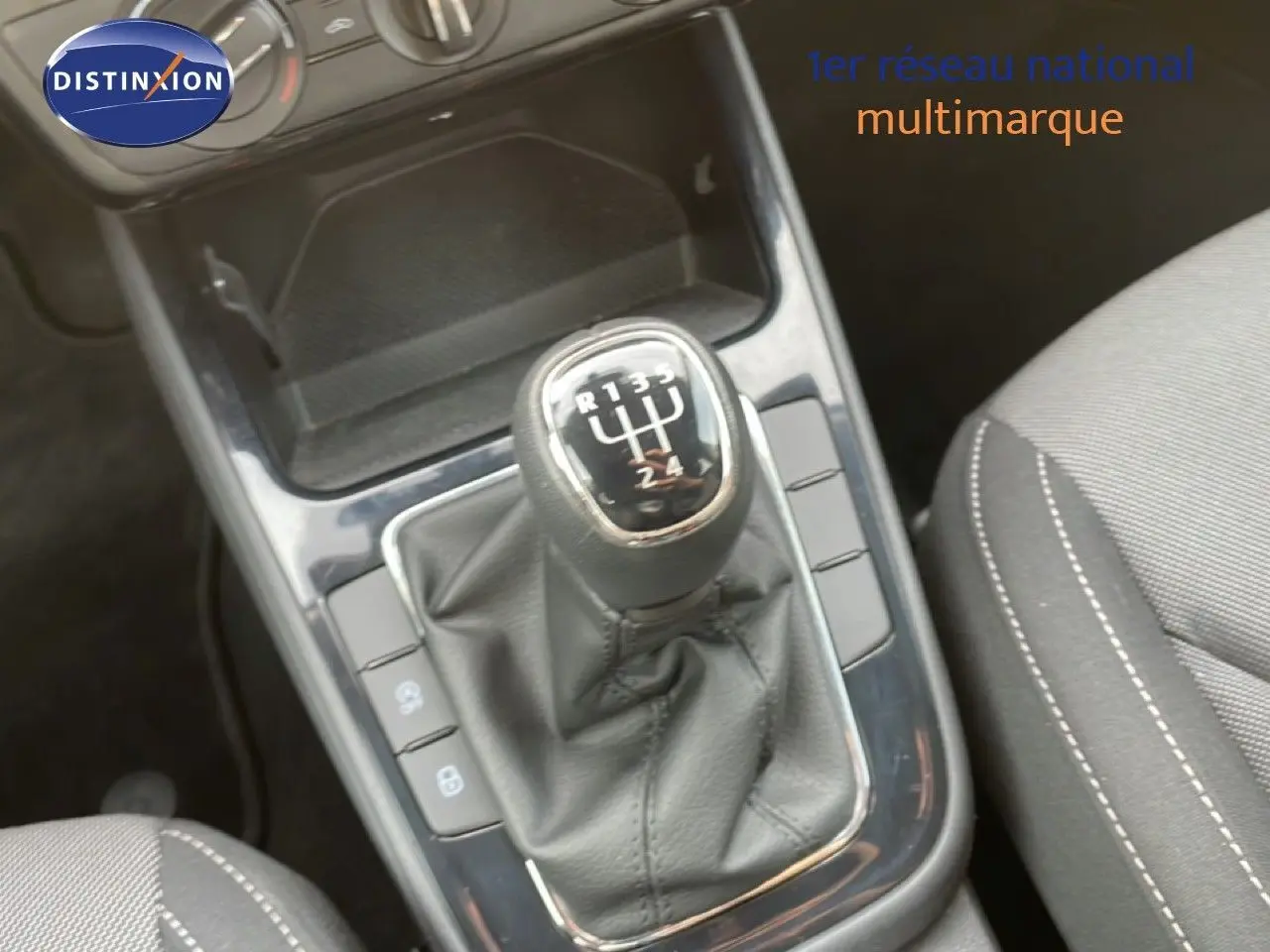 Gros plan sur le levier de vitesses manuel noir et la console centrale d’une Skoda Fabia blanc glacier, intérieur tissu gris.