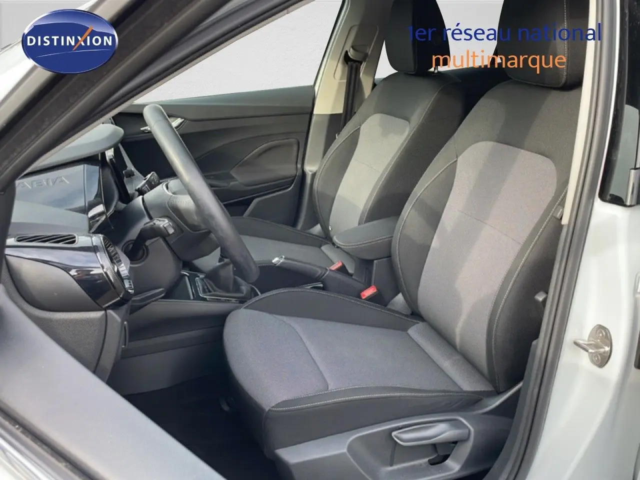 Vue intérieure côté conducteur de la Skoda Fabia blanc glacier 2025, sièges tissu gris et volant cuir multifonction.