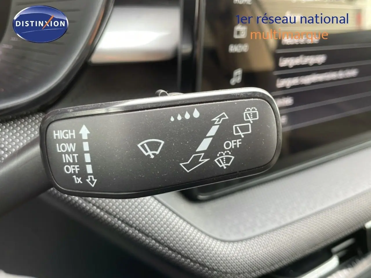 Gros plan sur la commande d’essuie-glace dans l’habitacle d’une Skoda Fabia blanc glacier, tableau de bord en arrière-plan flou.