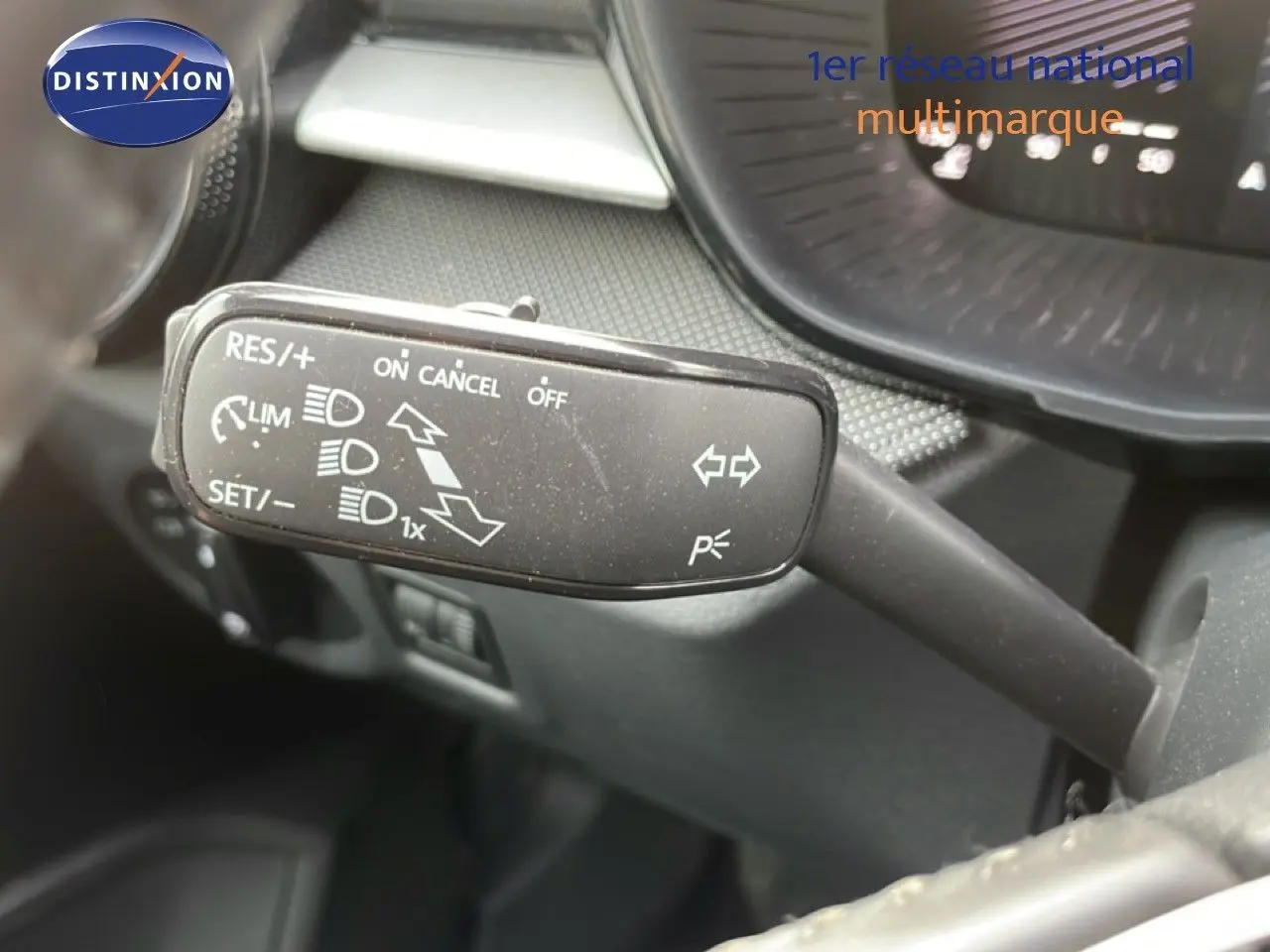 Gros plan sur la commande de régulateur de vitesse à gauche du volant dans l’habitacle d’une Skoda Fabia blanche.