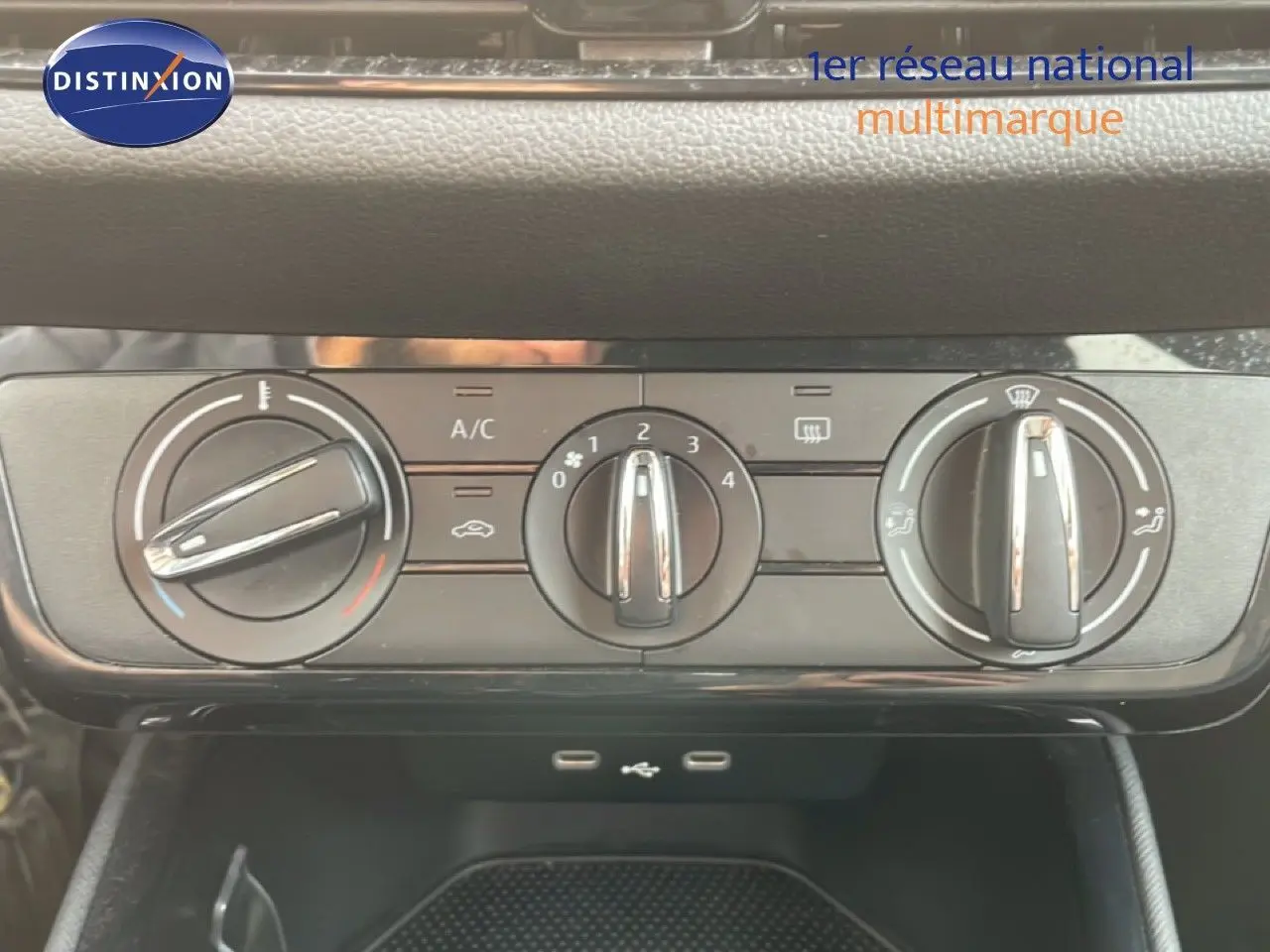 Vue rapprochée des commandes de climatisation d'une Skoda Fabia blanche Glacier, avec boutons rotatifs noirs et chrome.