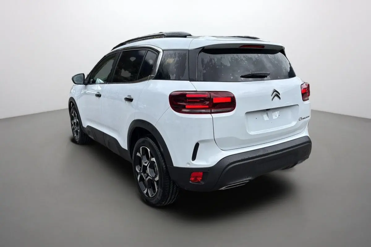 Vue 3/4 arrière droite d'un Citroën C5 Aircross Hybrid blanc Okenite avec jantes biton et feux LED distinctifs.