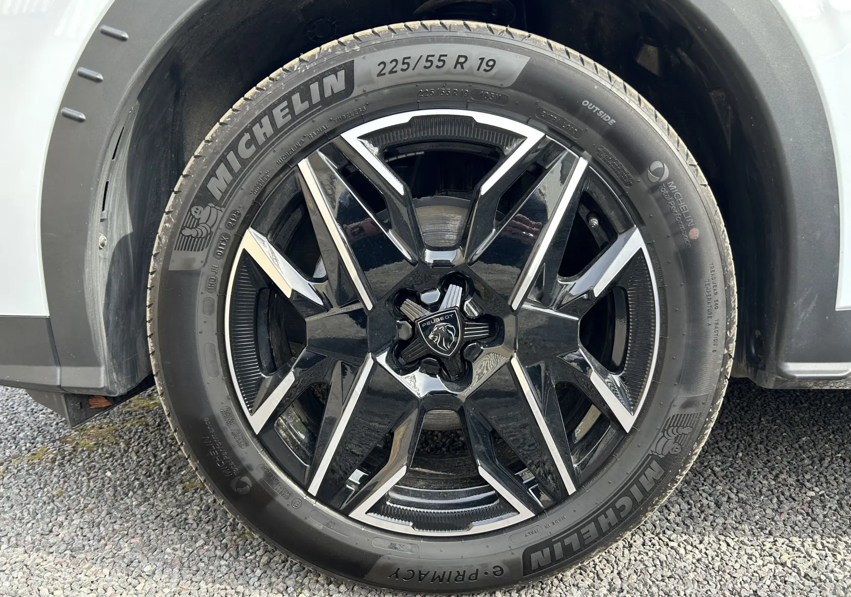 Gros plan sur la roue avant gauche d’un Peugeot 3008 blanc Okenite, jante alliage noire et argent avec pneu Michelin.