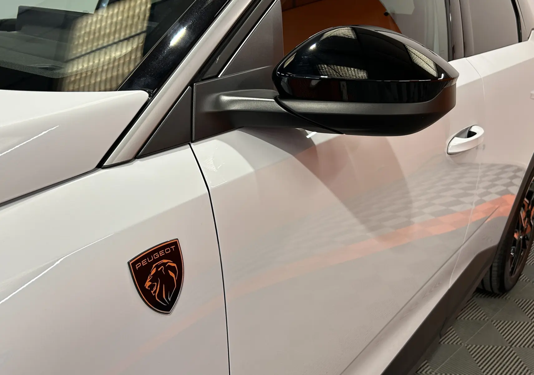 Détail du côté gauche blanc Okenite du Peugeot 3008 III Hybrid avec rétroviseur noir brillant et logo Peugeot bronze.