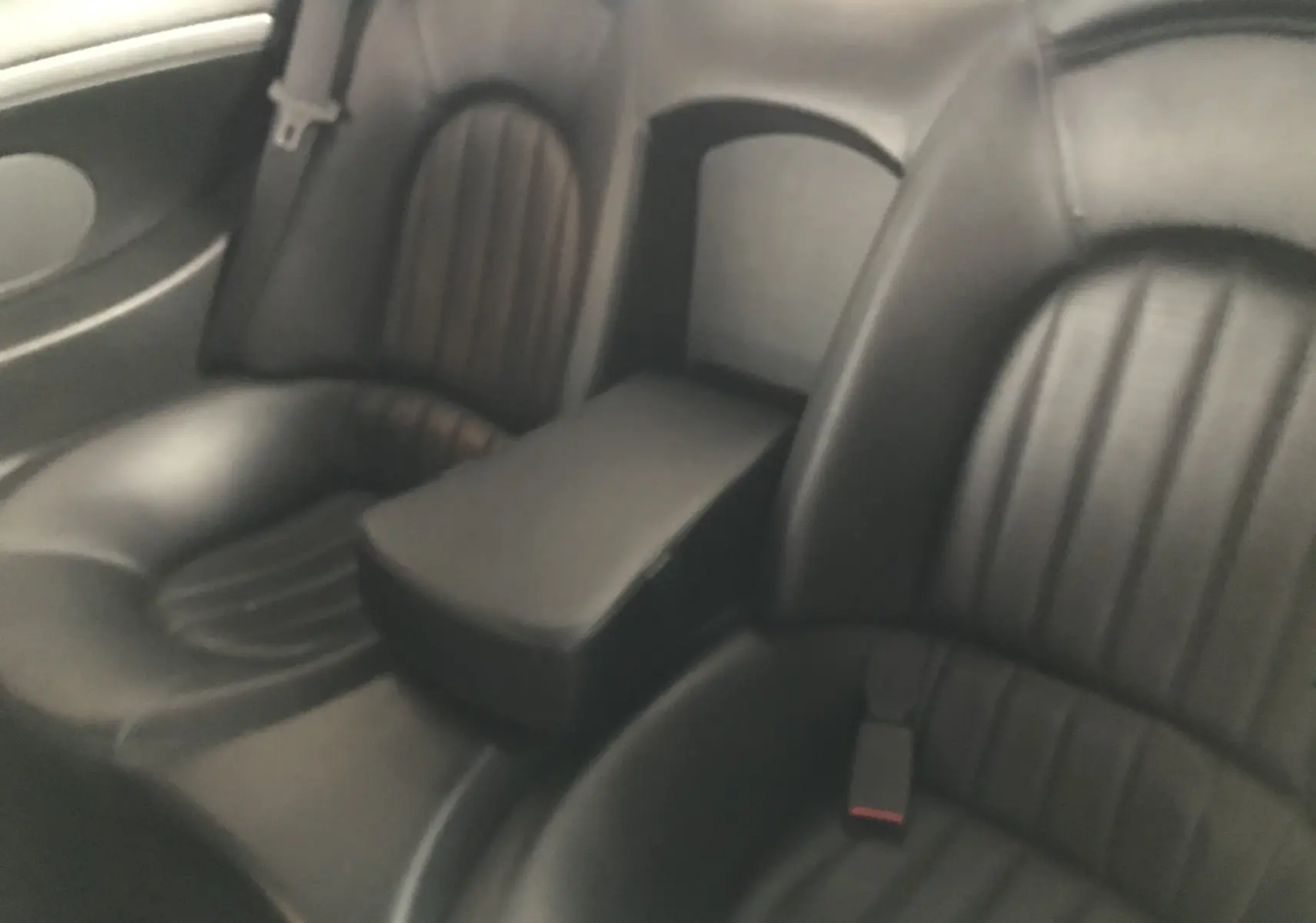 Vue rapprochée des sièges arrière en cuir noir de la Maserati Coupé 2003, soulignant l'accoudoir central.