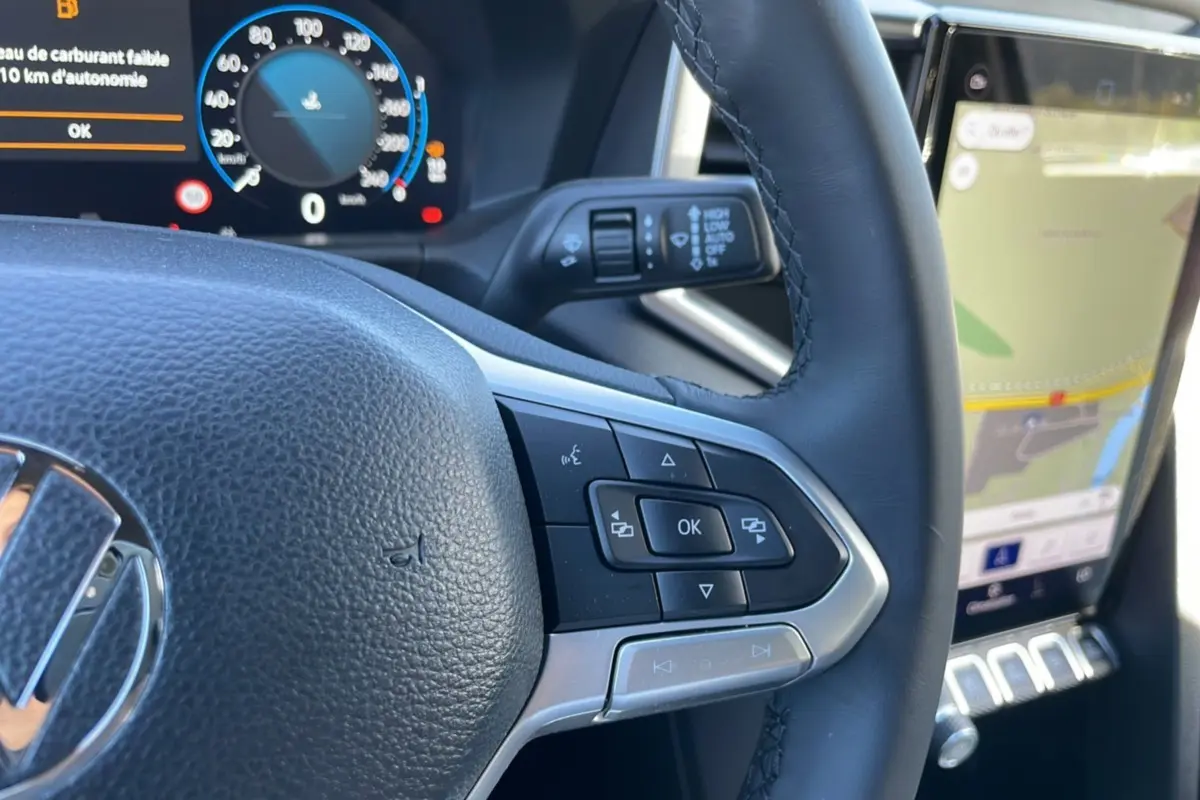 Gros plan sur le volant en cuir du Volkswagen Amarok blanc 2025, avec commandes multifonctions et tableau de bord numérique.