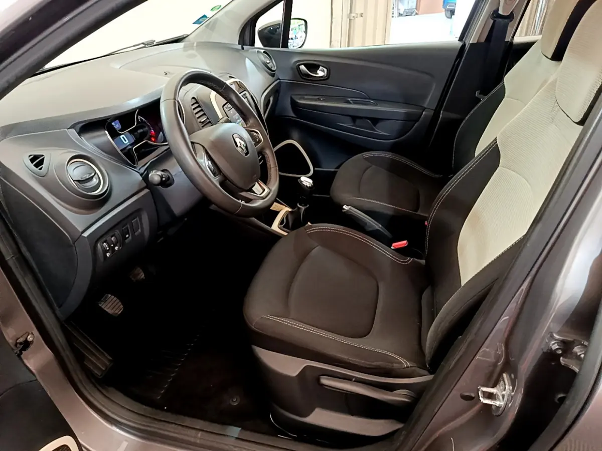 Vue intérieure côté conducteur du Renault Captur Business gris foncé de 2018, montrant le volant cuir et la console centrale.