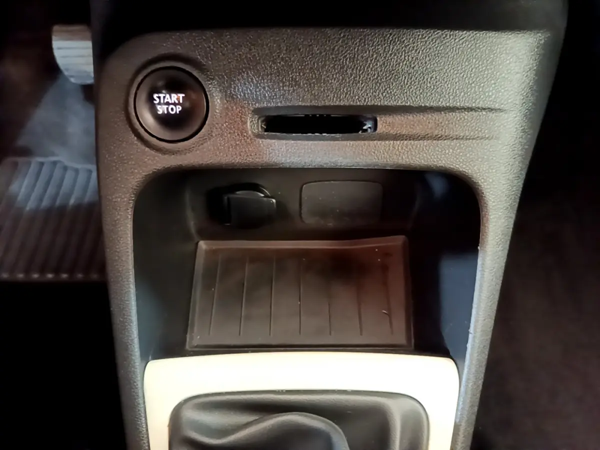 Gros plan sur la console centrale du Renault Captur Business avec bouton start/stop et prise 12V sous tableau de bord noir.