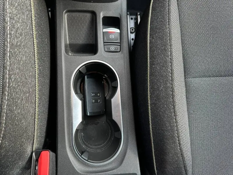 Vue plongeante sur la console centrale noire du Renault Captur 2025 avec porte-gobelets et clé électronique posée.