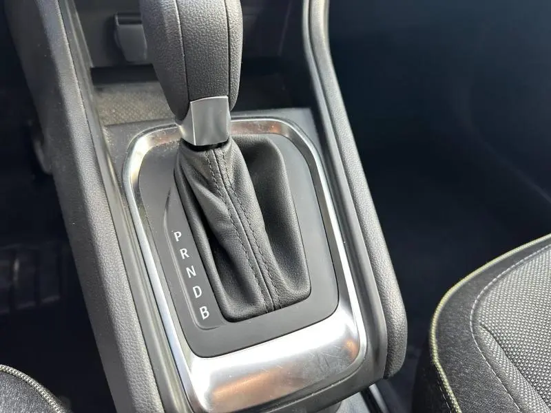 Gros plan sur la commande de boîte automatique noire avec soufflet cuir dans l’habitacle du Renault Captur rouge.
