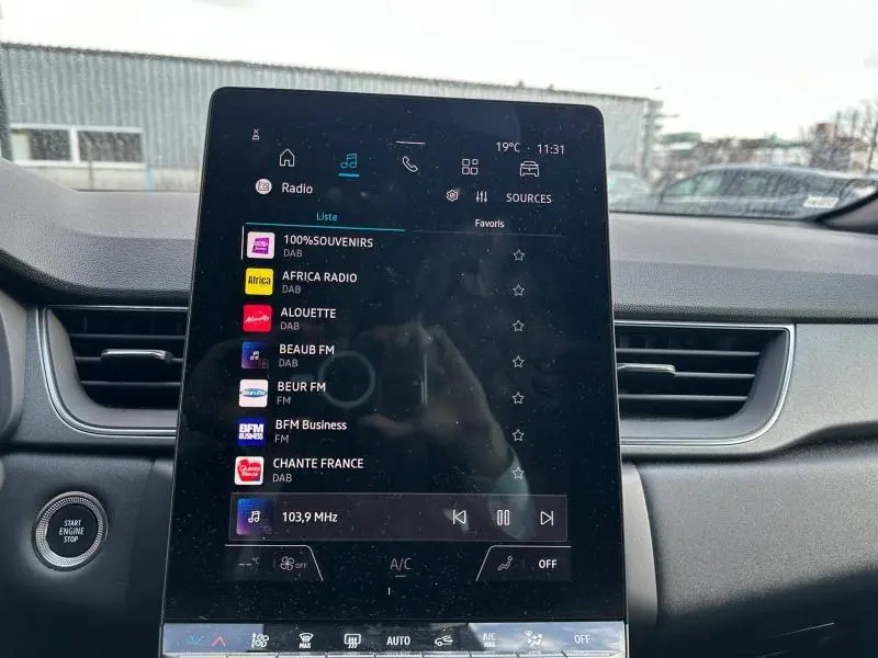 Écran tactile central affichant la radio dans l’habitacle du Renault Captur rouge, vue de face intérieure.