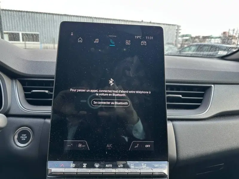 Vue intérieure centrée sur l'écran tactile vertical du tableau de bord du Renault Captur rouge 2025.