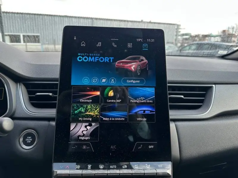 Écran tactile central du tableau de bord du Renault Captur rouge, affichant les modes de conduite et aides à la conduite.