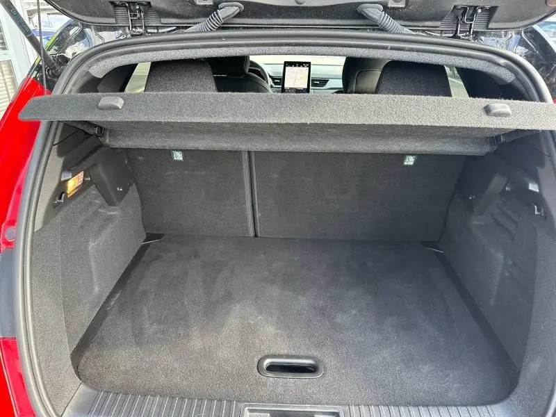 Coffre ouvert vu de l'arrière du Renault Captur rouge, montrant un espace de chargement propre et la tablette cache-bagages.
