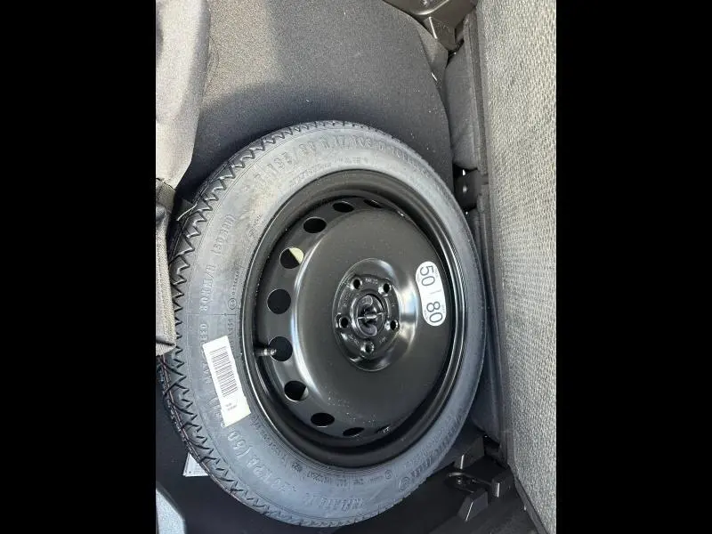 Pneu de secours noir en jante acier dans le coffre du Renault Captur rouge 2025, vue rapprochée intérieure.