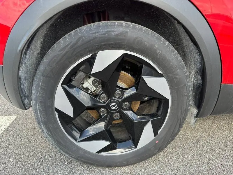 Gros plan sur la roue avant droite avec jante alu noire et argent du Renault Captur rouge Flamme 2025.