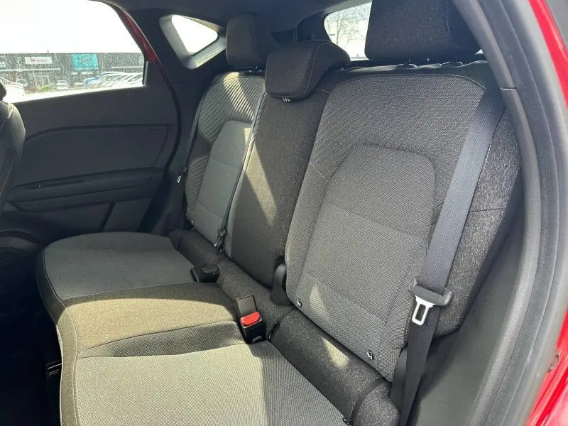 Vue intérieure côté droit des sièges arrière gris foncé du Renault Captur rouge 2025, avec ceintures de sécurité visibles.