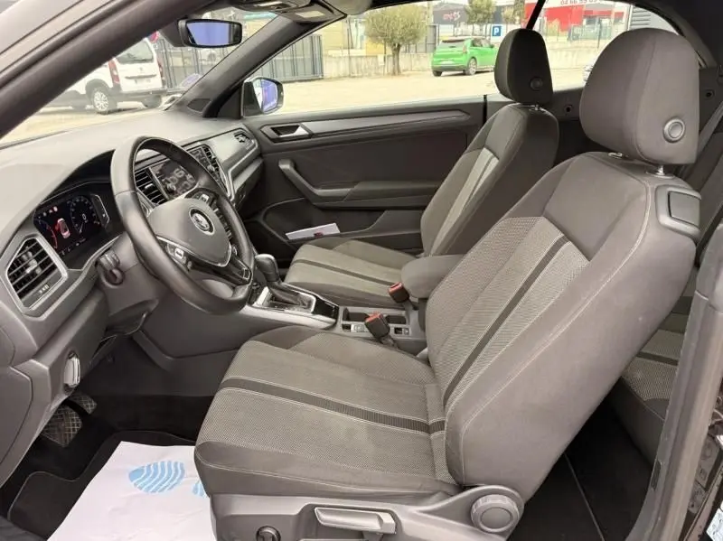 Vue intérieure côté conducteur du Volkswagen T-Roc Cabriolet noir métal 2020, montrant les sièges et tableau de bord.