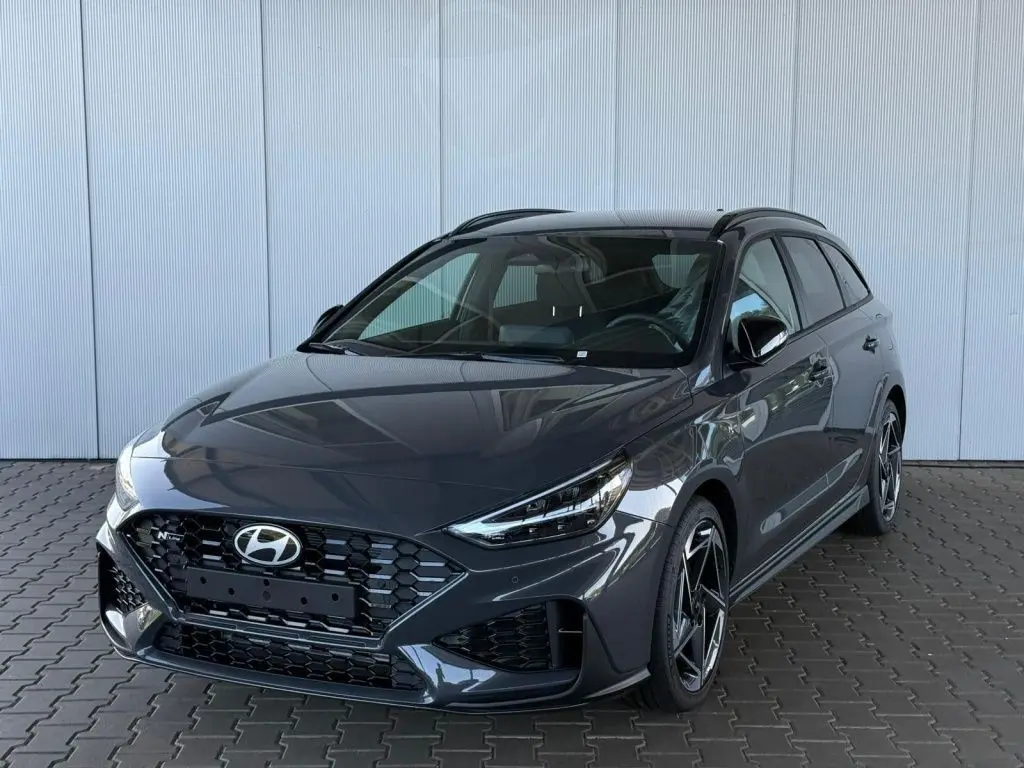 Vue 3/4 avant droite d'une Hyundai i30 SW N-Line gris foncé avec calandre hexagonale et jantes alliage distinctives.