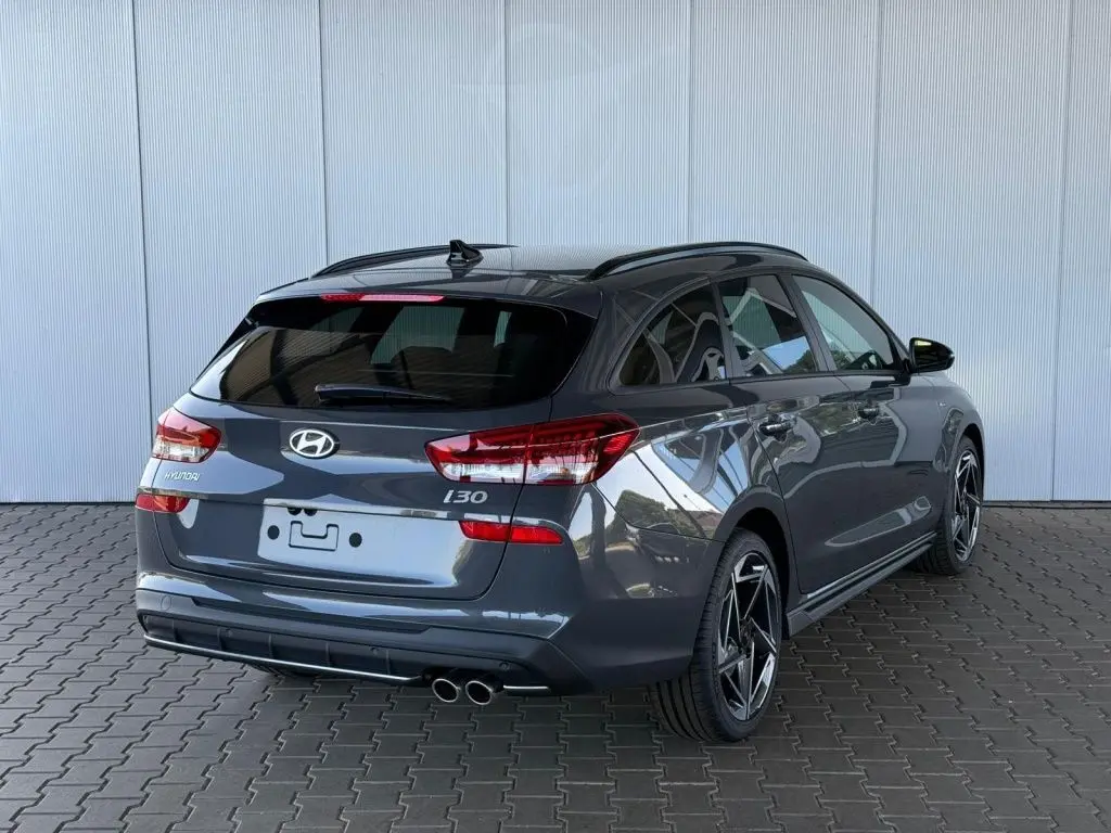 Vue 3/4 arrière droite d'une Hyundai i30 SW N-LINE gris foncé avec double sortie d'échappement et jantes sport.