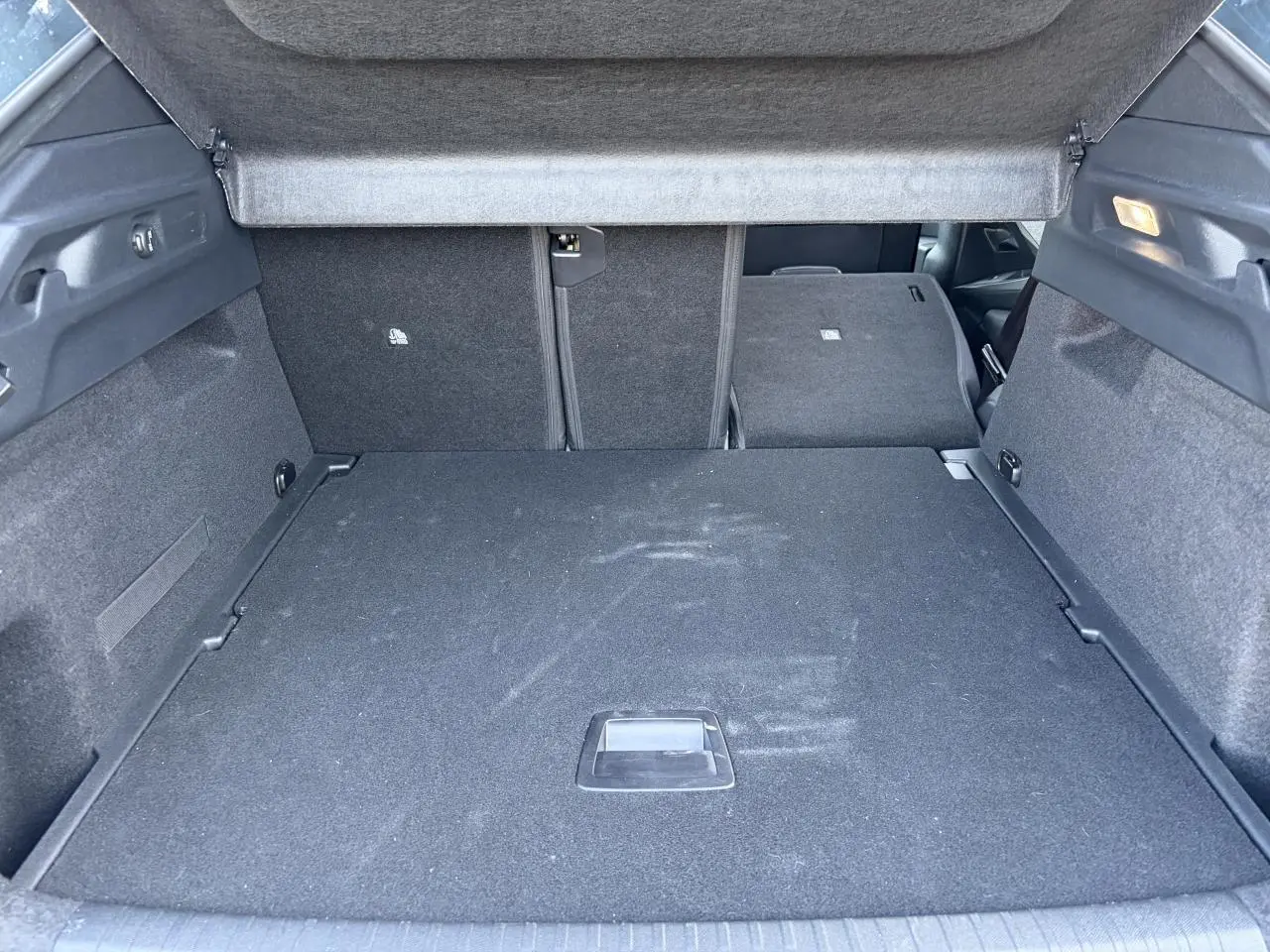 Coffre ouvert de Peugeot 3008 bleu Ingaro, vue intérieure arrière avec banquette partiellement rabattue.