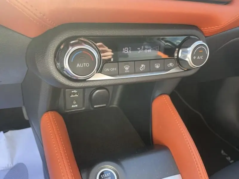 Vue rapprochée de la console centrale du Nissan Micra 2017 noir, avec commandes de climatisation et garnitures orange.