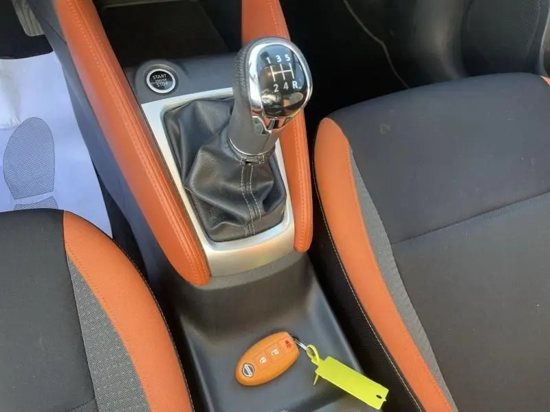 Vue rapprochée de la console centrale d'une Nissan Micra 2017 noire, avec levier de vitesse manuel et clé orange visible.