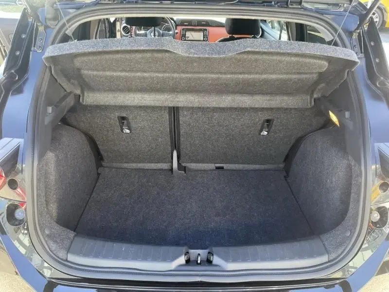 Coffre ouvert vu de l'arrière d'une Nissan Micra noire 2017, intérieur du coffre en tissu gris et planche de séparation relevée.