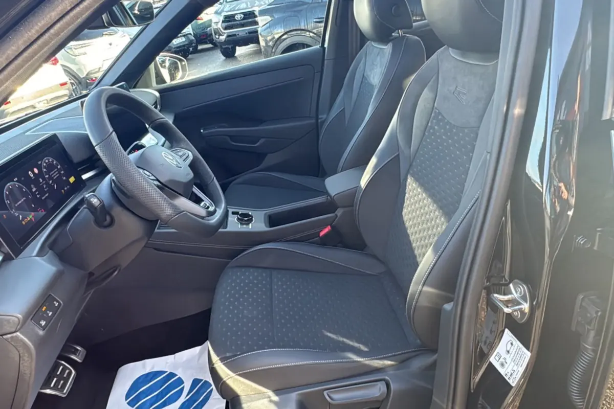 Vue intérieure côté conducteur du Volkswagen T-Roc noir ebène 2026, sièges tissu R-Line et tableau de bord digital.