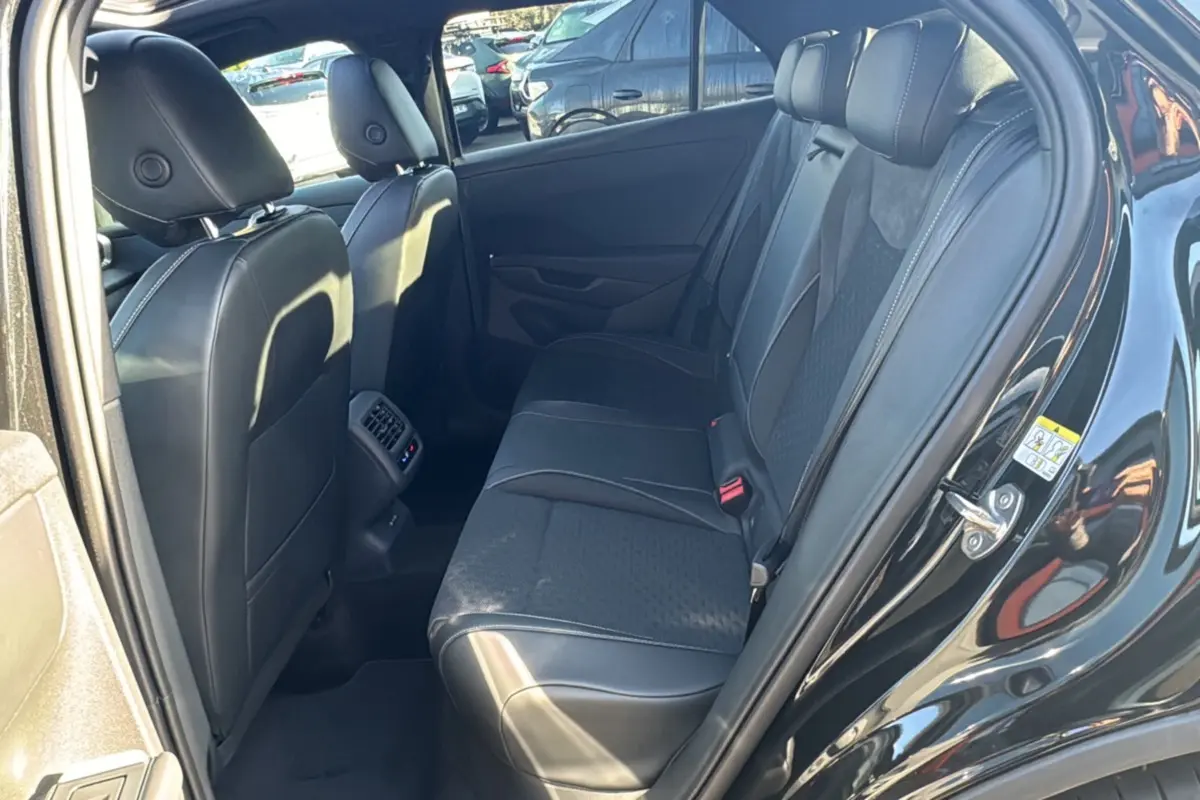 Vue intérieure côté arrière droit du Volkswagen T-Roc noir ebène, montrant la banquette arrière en tissu et cuir avec appuie-têtes.