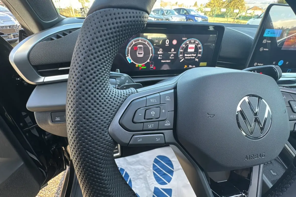 Gros plan sur le volant cuir multifonctions noir du Volkswagen T-Roc 2026 avec tableau de bord digital lumineux.