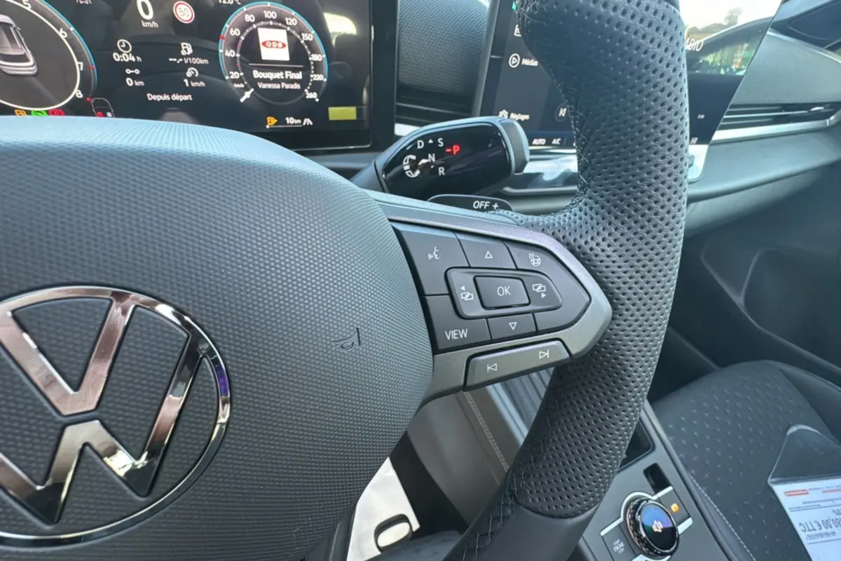 Gros plan sur le volant cuir perforé et les commandes multifonctions du tableau de bord du Volkswagen T-Roc noir.