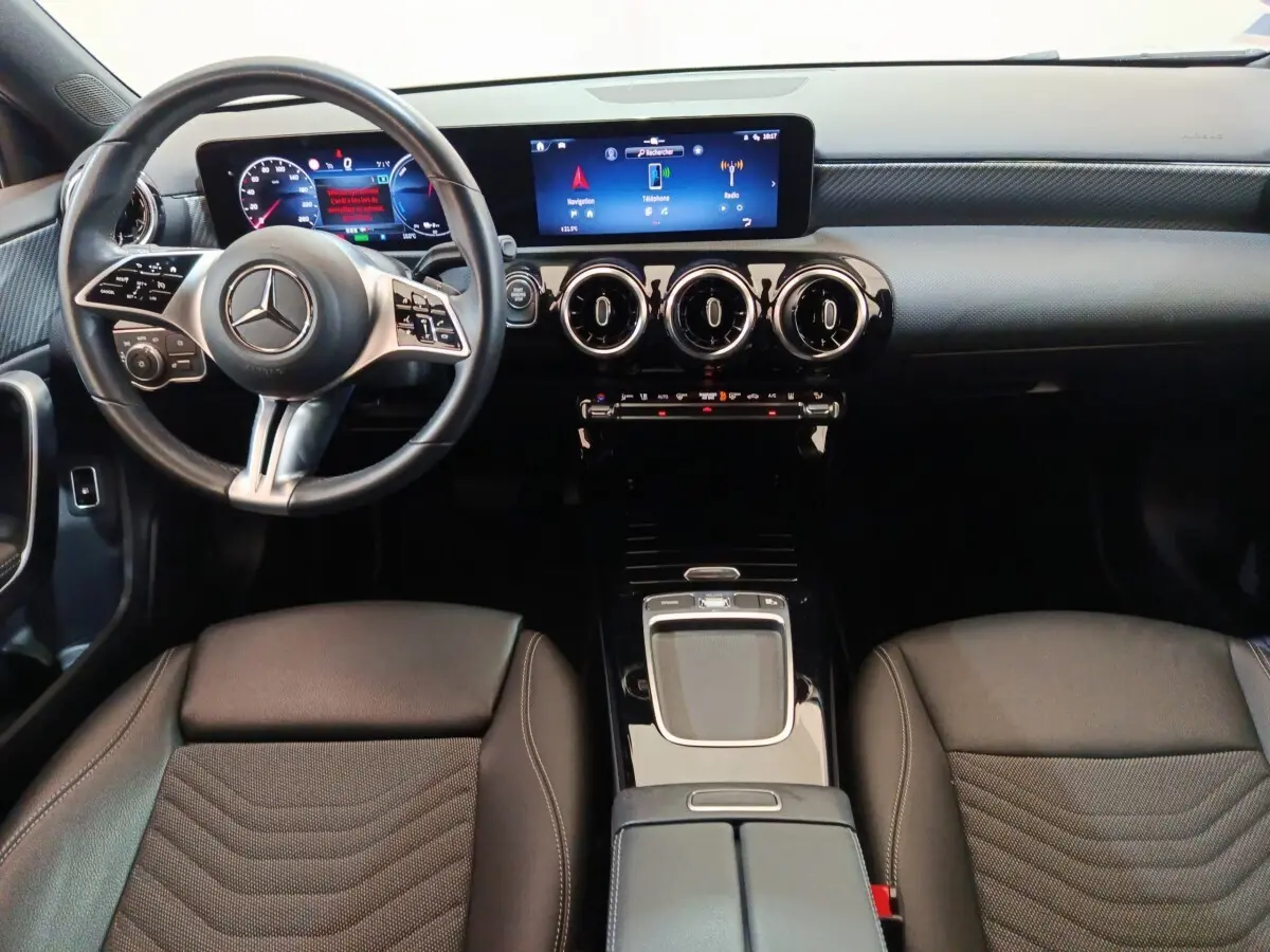 Vue intérieure avant du Mercedes GLA 250 e Business Line 2023, tableau de bord noir avec écran tactile et volant cuir multifonctions.