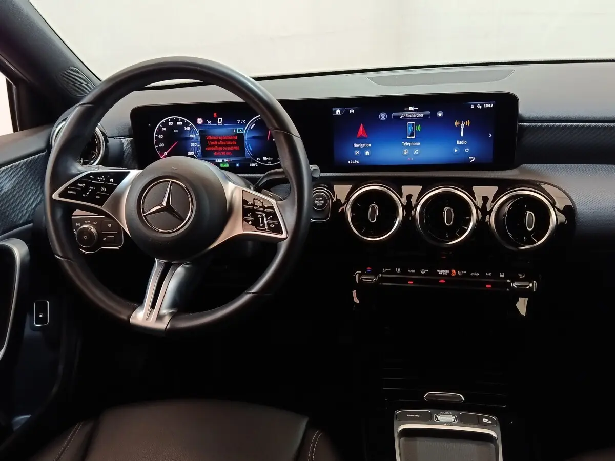 Vue intérieure du tableau de bord et volant cuir Mercedes GLA 250 e 2023 avec écran tactile large et aérateurs ronds chromés.