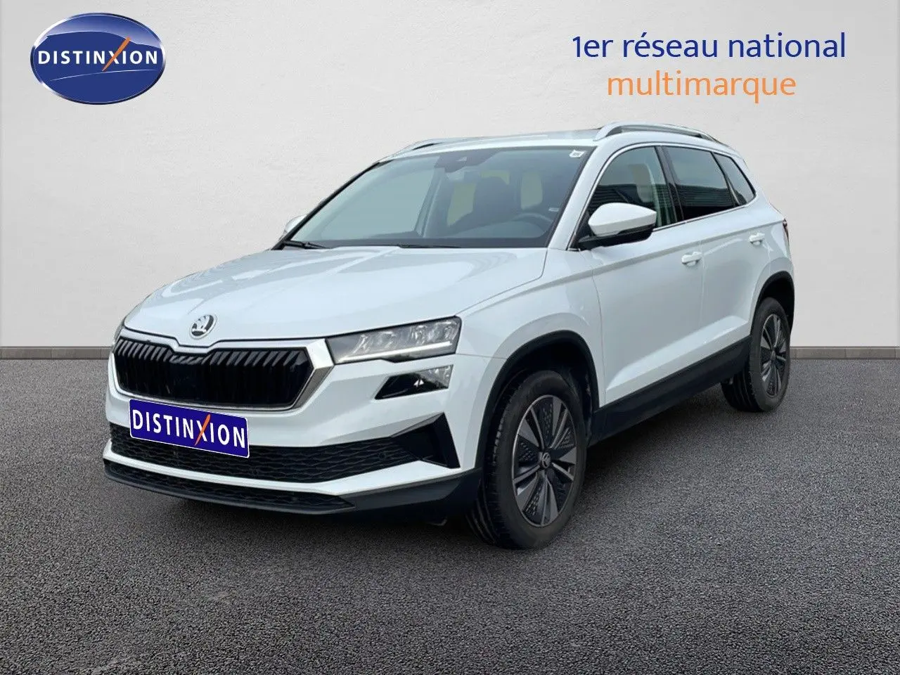 SUV Skoda Karoq blanc glacier vu en 3/4 avant droit, avec calandre noire et jantes bi-ton.