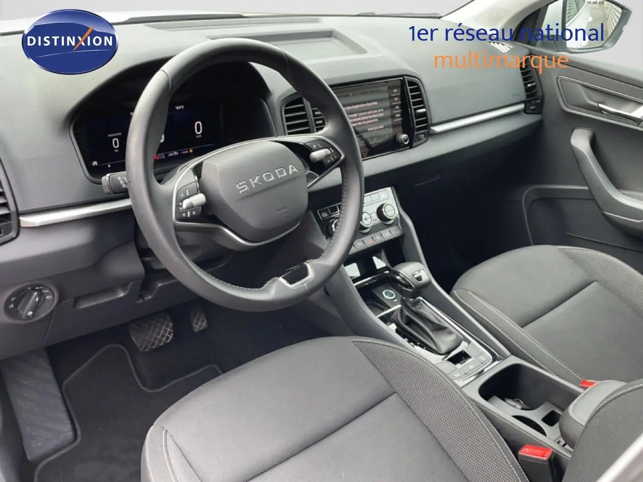 Vue intérieure côté conducteur du Skoda Karoq blanc glacier 2025, avec tableau de bord numérique et volant multifonction cuir.